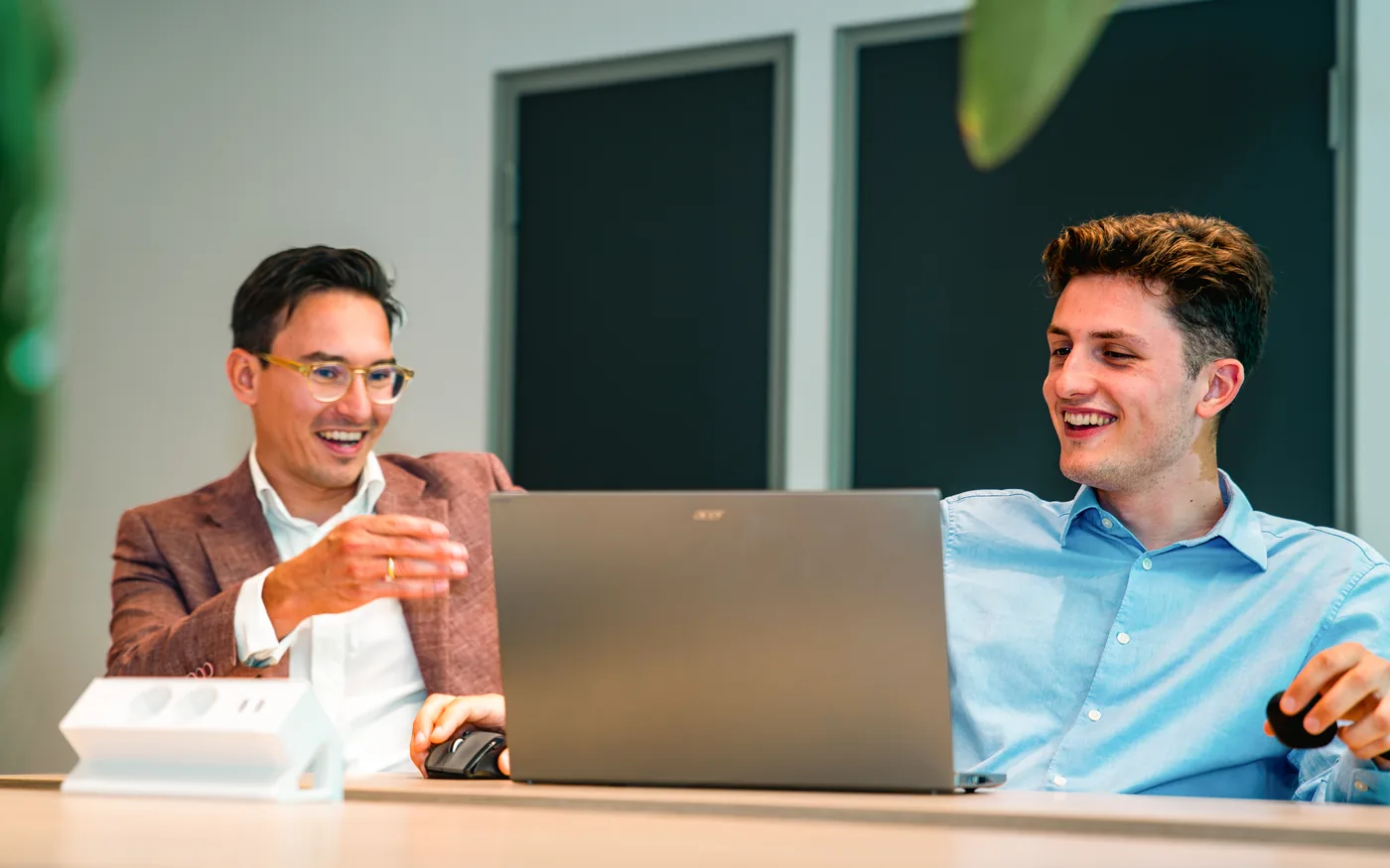 Twee Newbit-consultants bekijken lachend een voorspelling op een laptopscherm